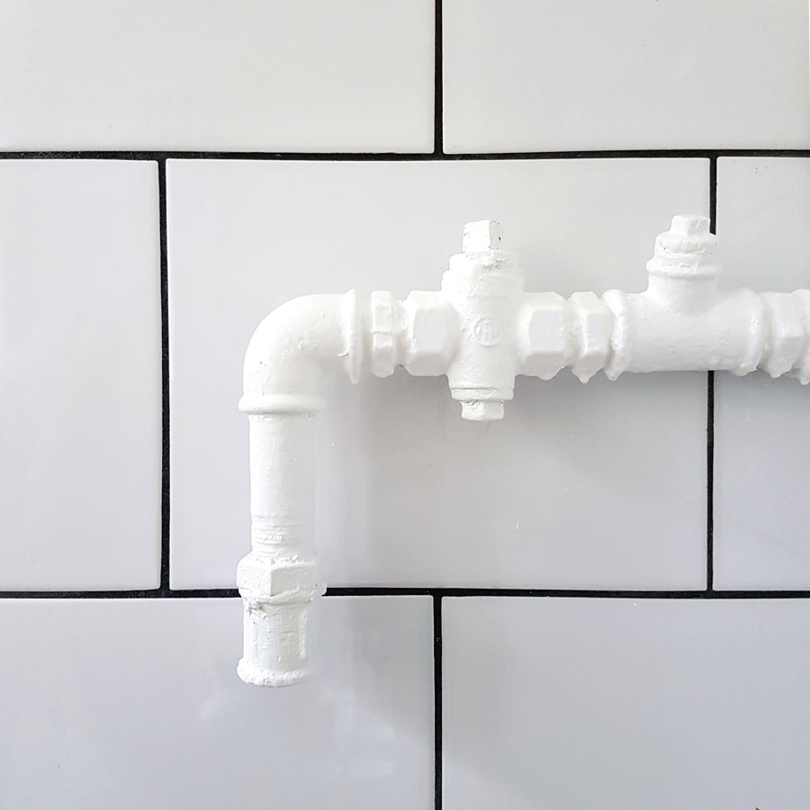 Poremontowe spełnianie marzeń małych - białe płytki, czarna fuga, rura